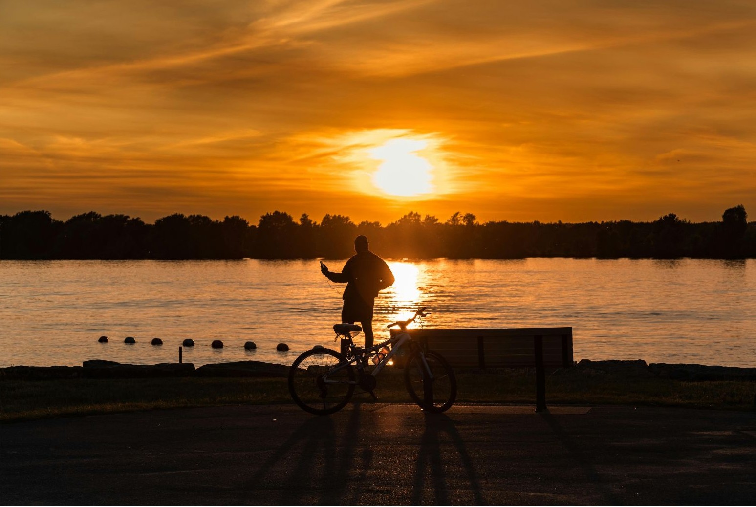 Obraz symboliczny przedstawia rowerzystę o zachodzie słońca nad jeziorem